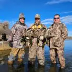 three men showing off their duck hunt results